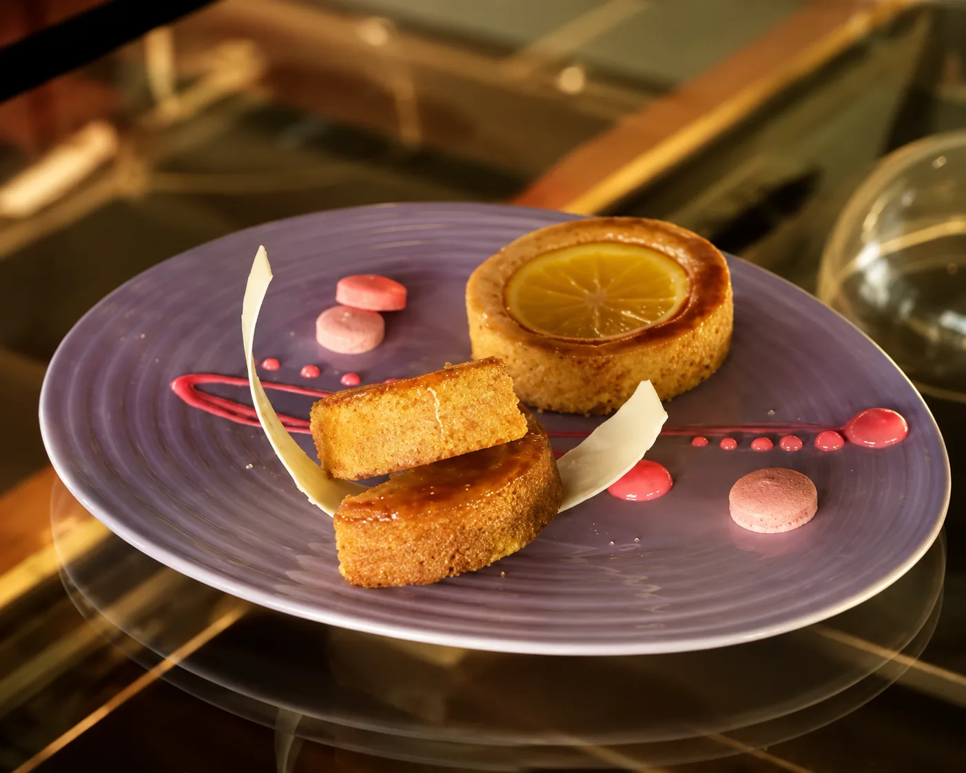 Citrus tart and glazed cake slices plated with berry sauce and white chocolate shards